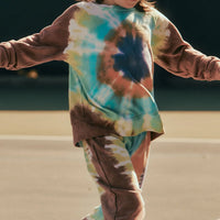 Child wearing a tie-dye shirt and pants on a basketball court