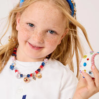 Young girl wearing a Dodgers jersey, headband, and jewelry holding a baseball.