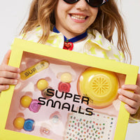 Child holding a 'Super Smalls' nail care kit with a yellow box.