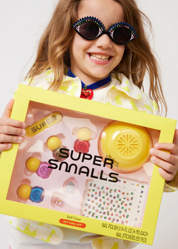 Child holding a 'Super Smalls' nail care kit with a yellow box.