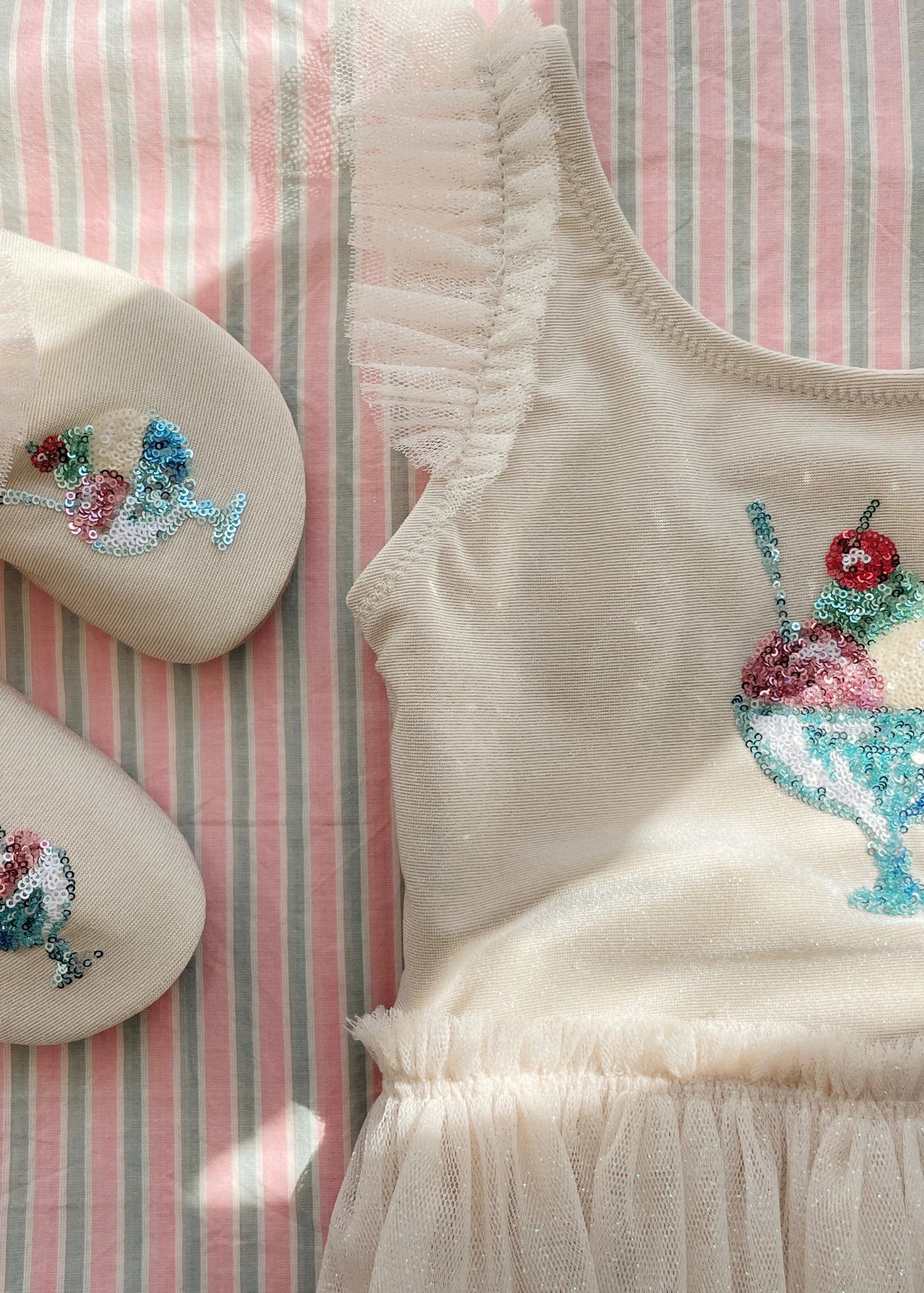 Beige sleeveless top with ice cream sundae design on a striped fabric background