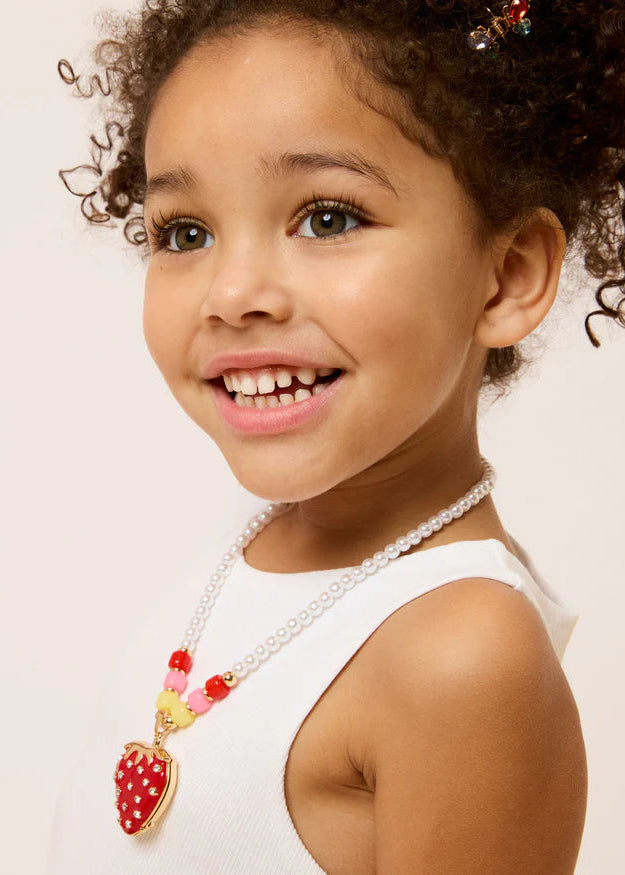 Young girl wearing a necklace with a strawberry pendant on a light background