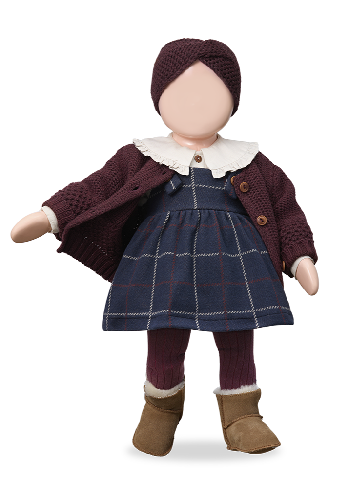 Doll wearing a plaid dress, brown cardigan, and boots on a white background