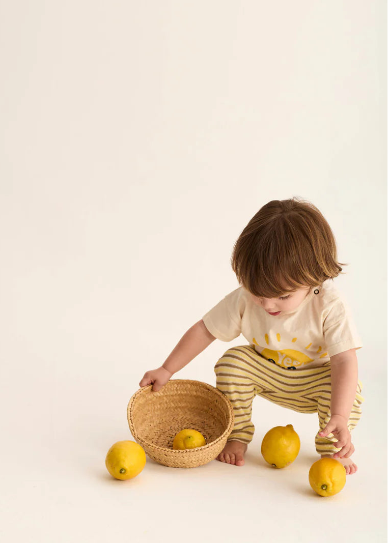 Child playing with lemons and a basket on a light background