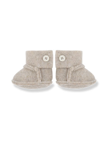 Pair of beige baby booties with buttons on a white background