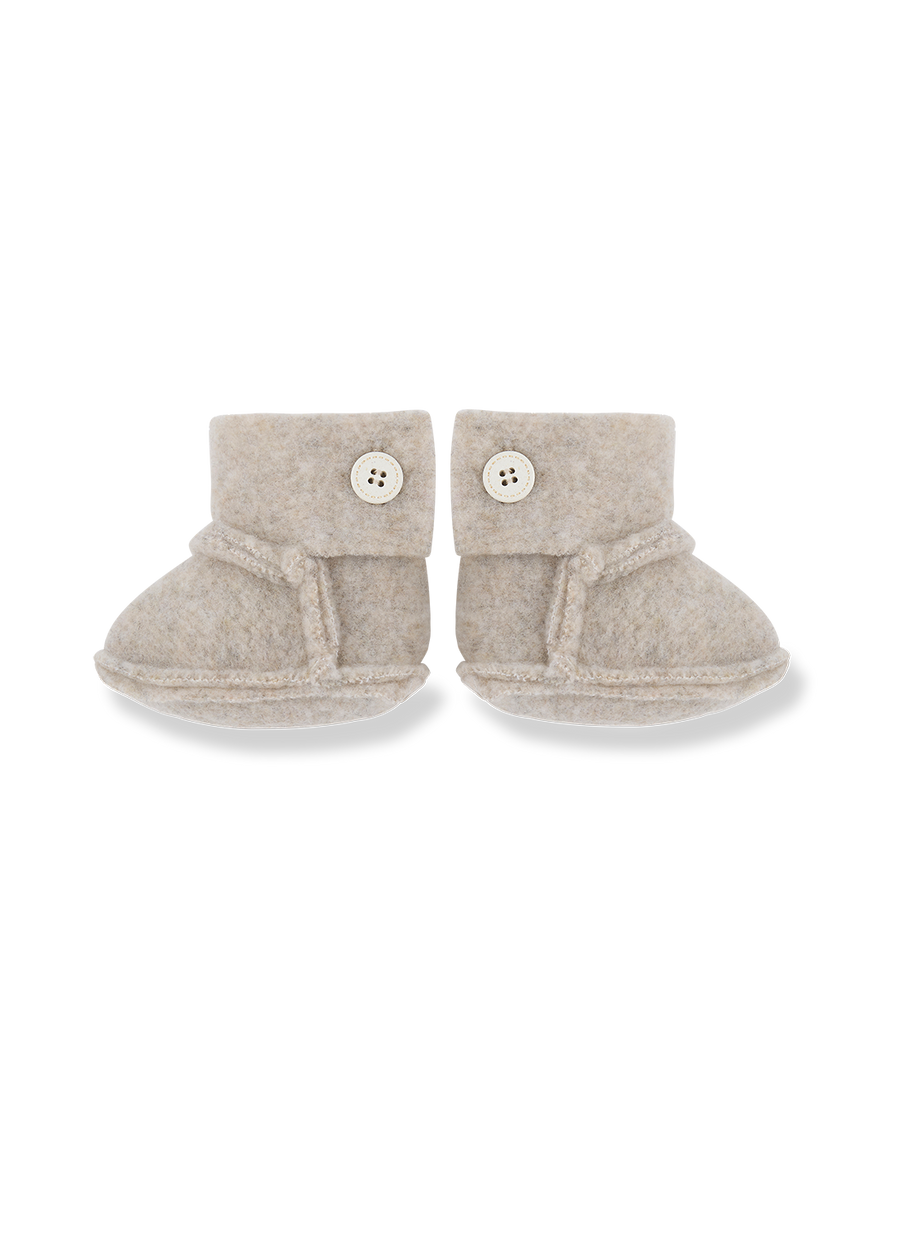Pair of beige baby booties with buttons on a white background