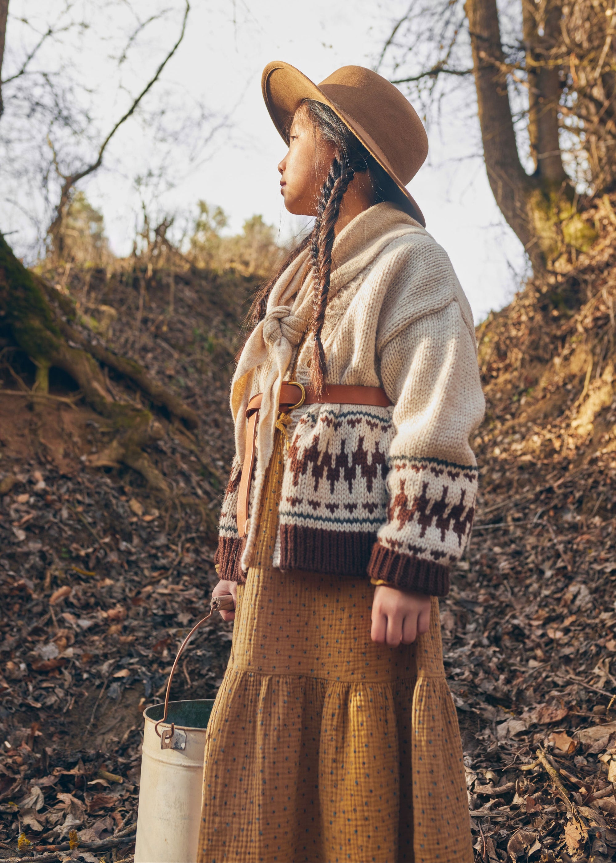 Person wearing a patterned sweater and hat in a forest setting
