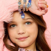 Young girl wearing multiple bracelets on a pink background