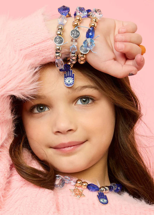 Young girl wearing multiple bracelets on a pink background