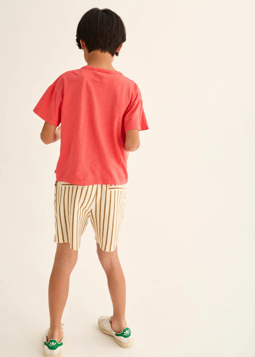 Person wearing a red t-shirt and striped shorts on a plain background