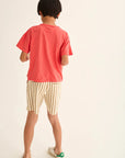 Person wearing a red t-shirt and striped shorts on a plain background