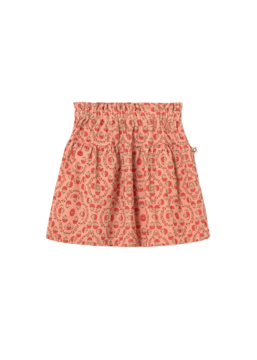 A children's pleated skirt with an elastic waistband, featuring a small-scale paisley pattern in coral pink, orange, and beige, shown flat on a light gray background.