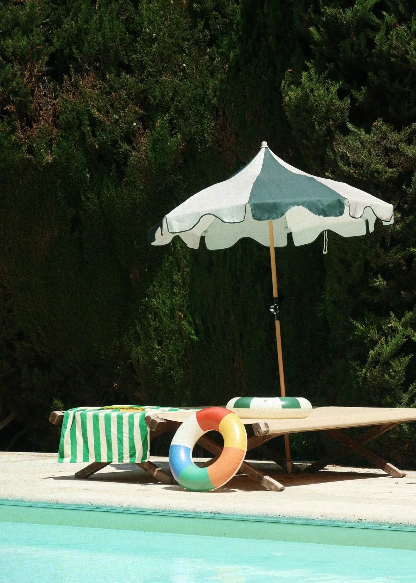 Poolside scene with a striped towel, inflatable ring, and umbrella