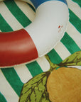Inflatable ring with red and blue colors on a green and white striped background