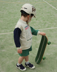 Child wearing a helmet and holding a skateboard on a tennis court