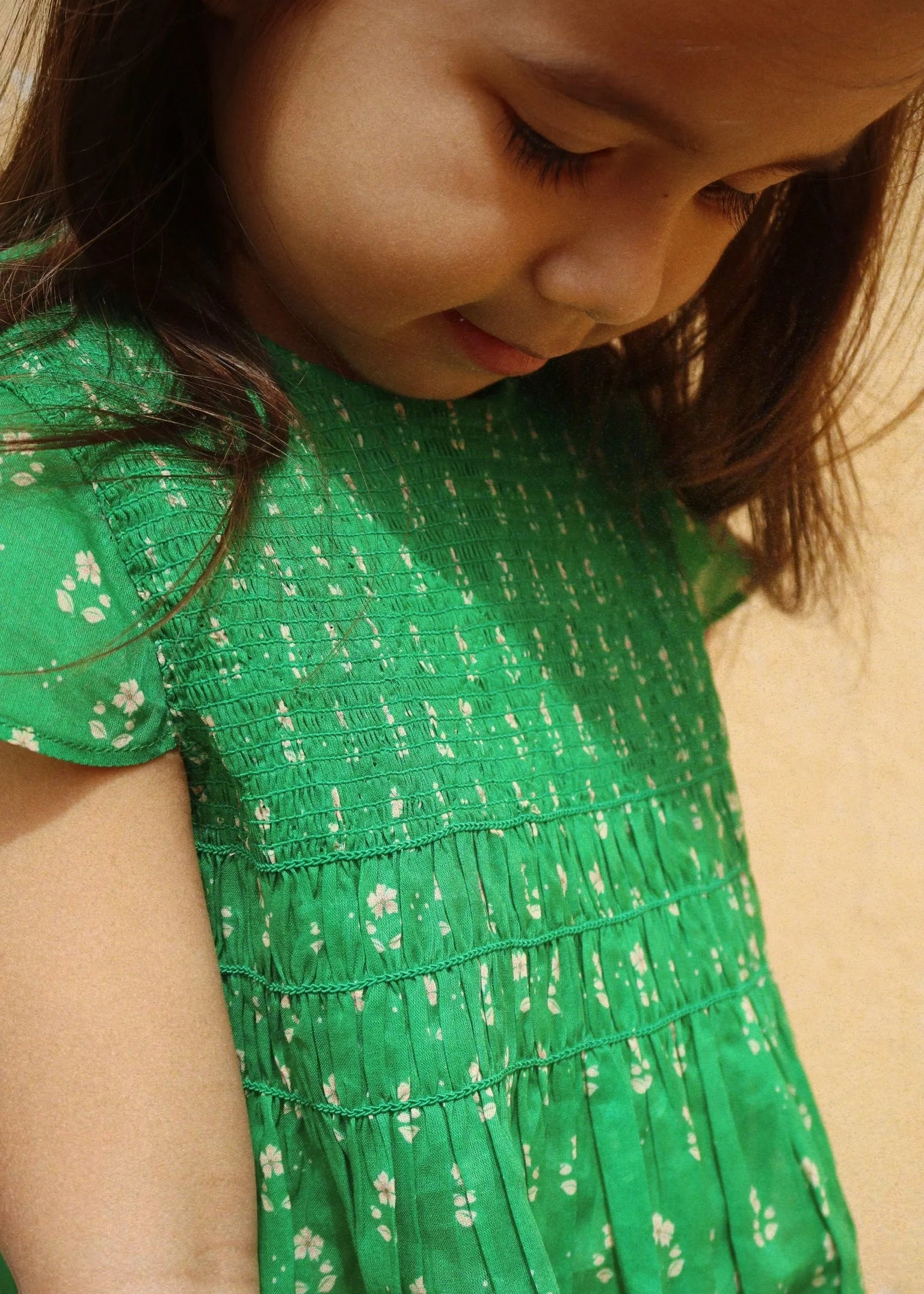 Close-up of a child wearing a green floral dress.