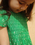 Close-up of a child wearing a green floral dress.