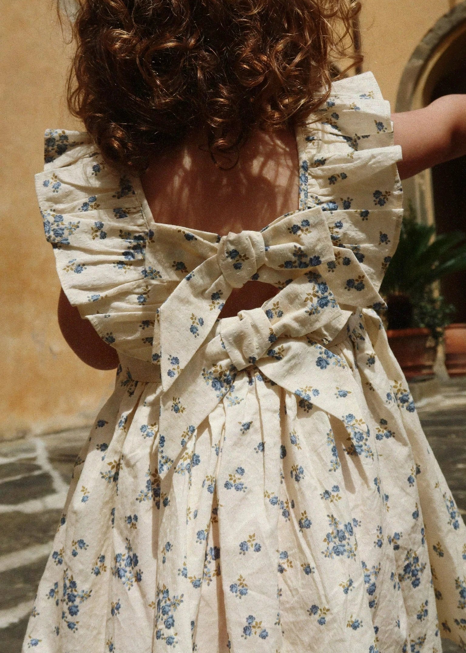 Woman wearing a floral dress with a bow detail in an outdoor setting