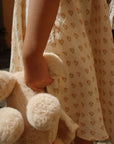 Person holding a teddy bear wearing a floral dress.