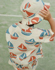 Child wearing a boat-patterned raincoat on a green surface