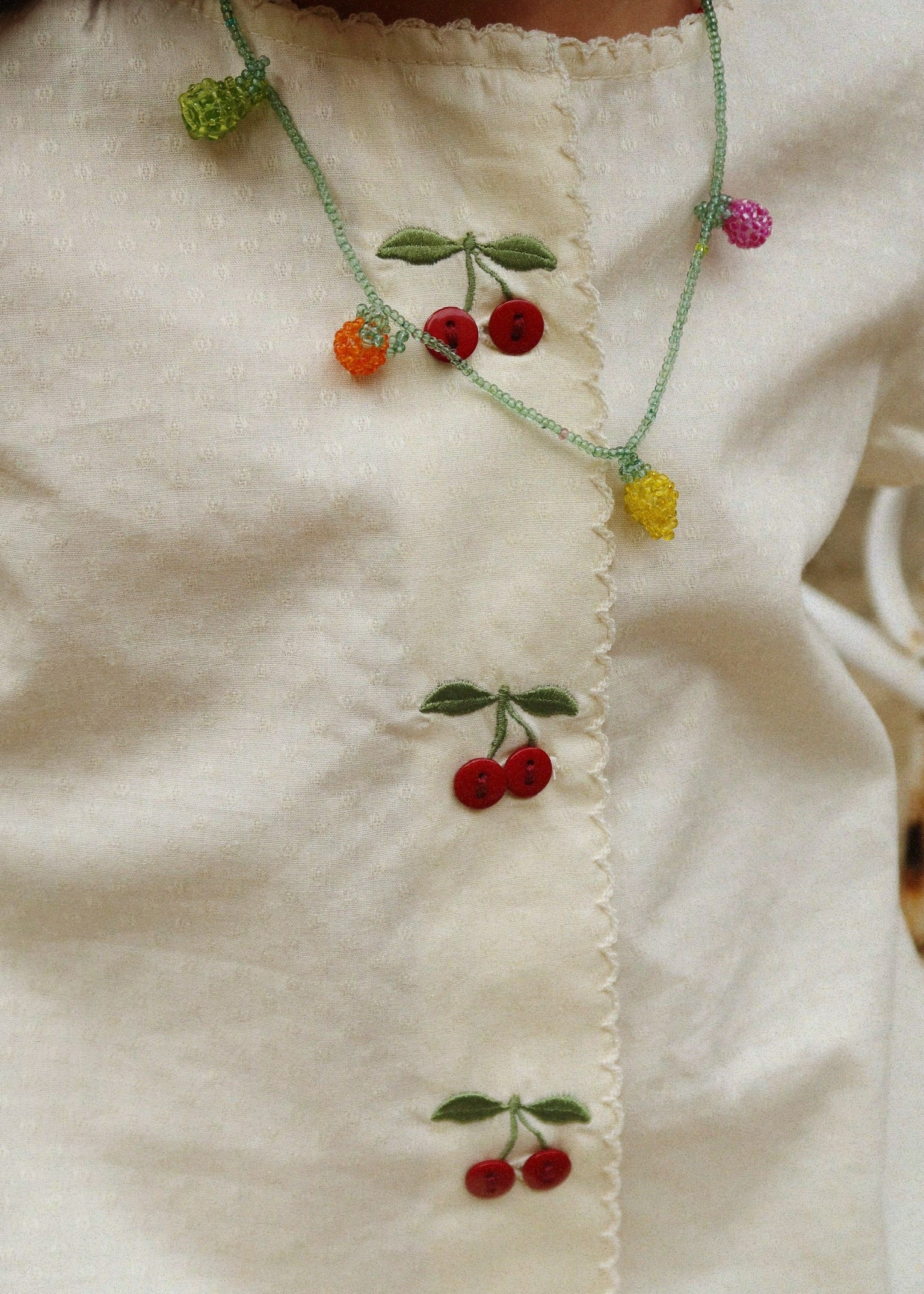 Necklace with cherry design on a white fabric background