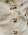 Necklace with cherry design on a white fabric background
