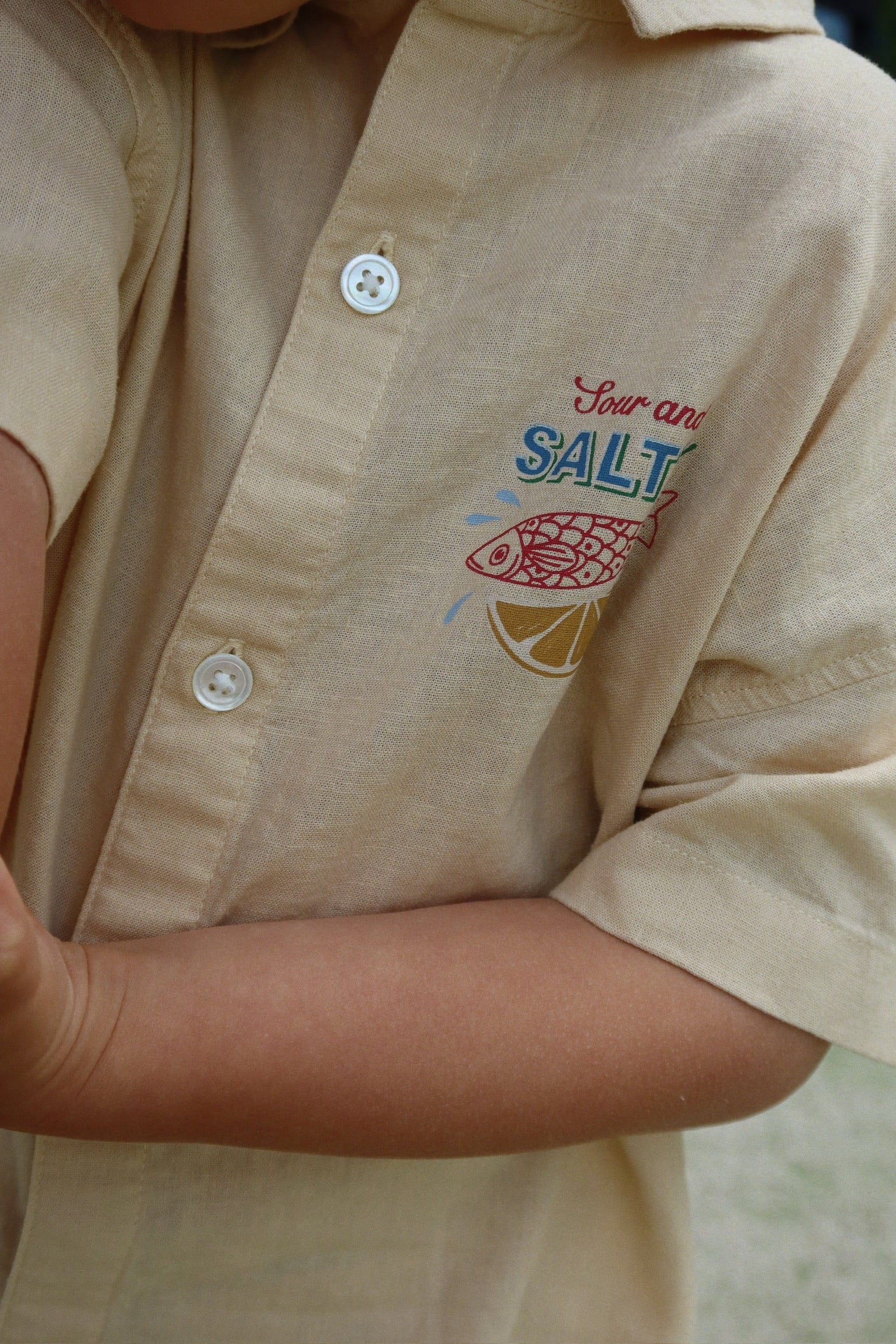 Beige shirt with 'Four and Salt' logo on a blurred background