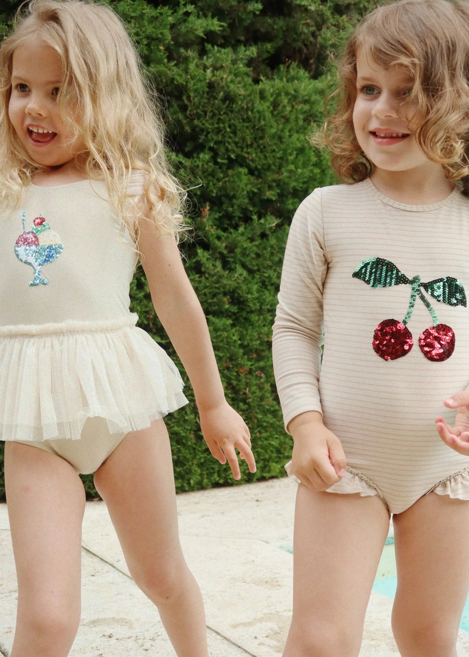 Two young girls wearing outfits with sequin embellishments outdoors.