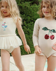 Two young girls wearing outfits with sequin embellishments outdoors.