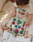 Baby playing with a colorful toy on a polka dot blanket
