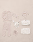 Baby clothing set including a onesie, hat, and booties on a beige background