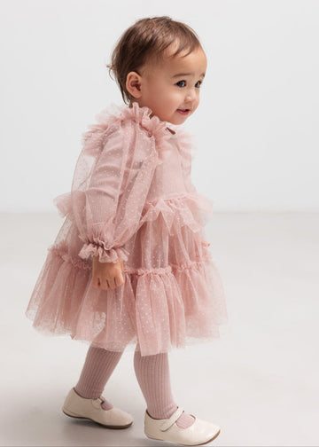 Child wearing a pink tulle dress on a white background