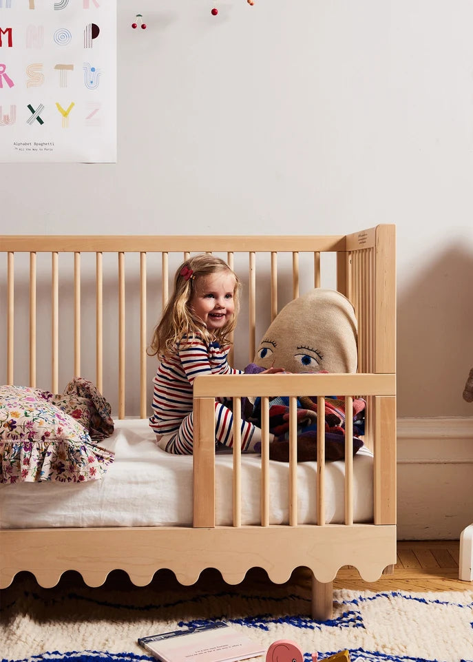 Child in a wooden crib with toys in a nursery setting