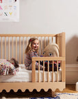 Child in a wooden crib with toys in a nursery setting