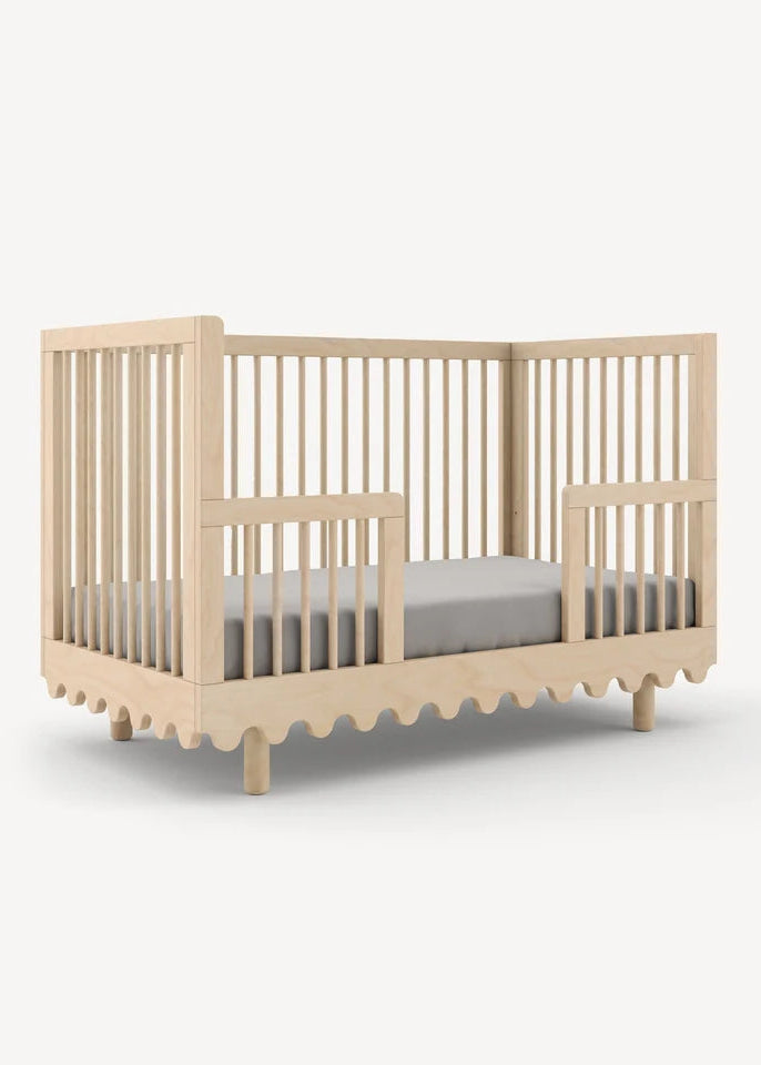 Beige crib with a gray mattress on a white background