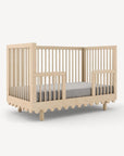 Beige crib with a gray mattress on a white background