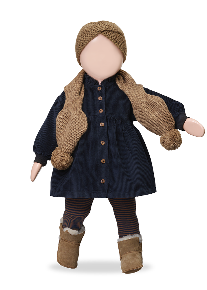 Doll wearing a navy dress with brown buttons, knitted scarf, and hat on a white background