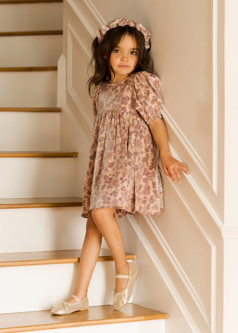 Young girl in a floral dress standing on a staircase