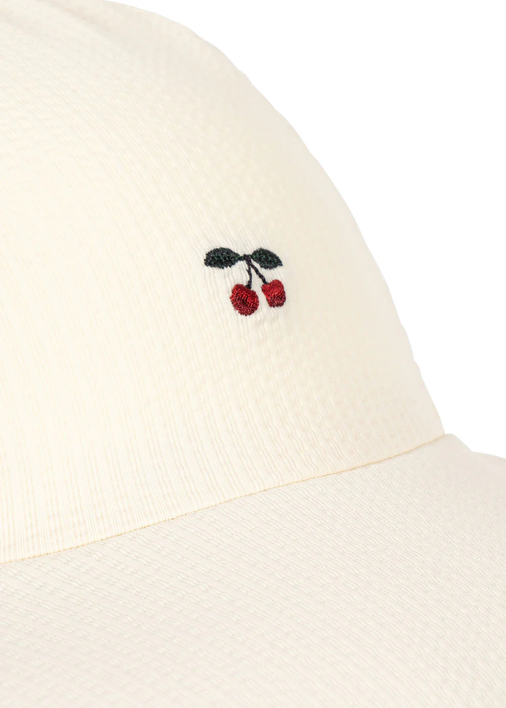 Close-up of a beige garment with embroidered cherries on a white background