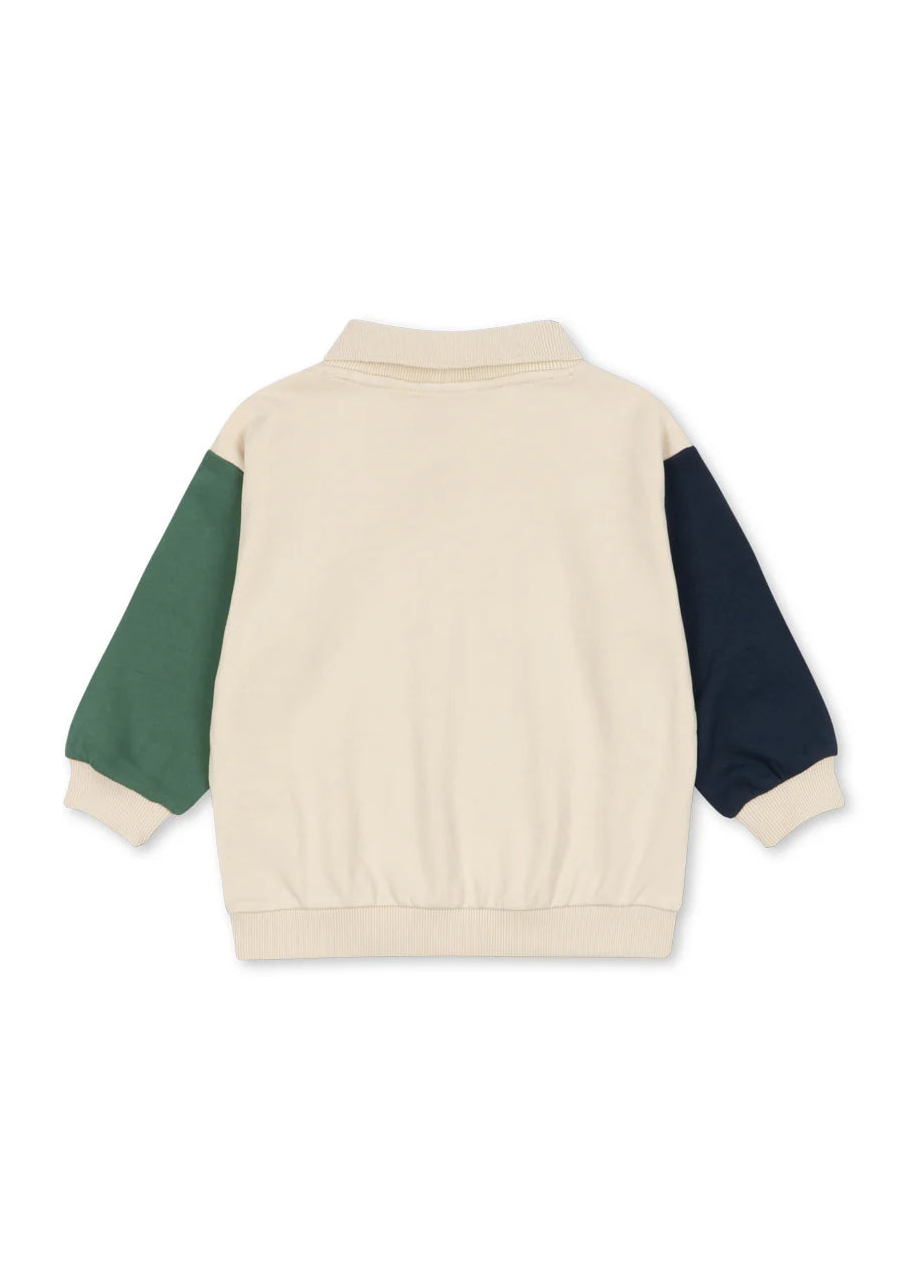 Beige sweater with green and navy sleeves on a white background