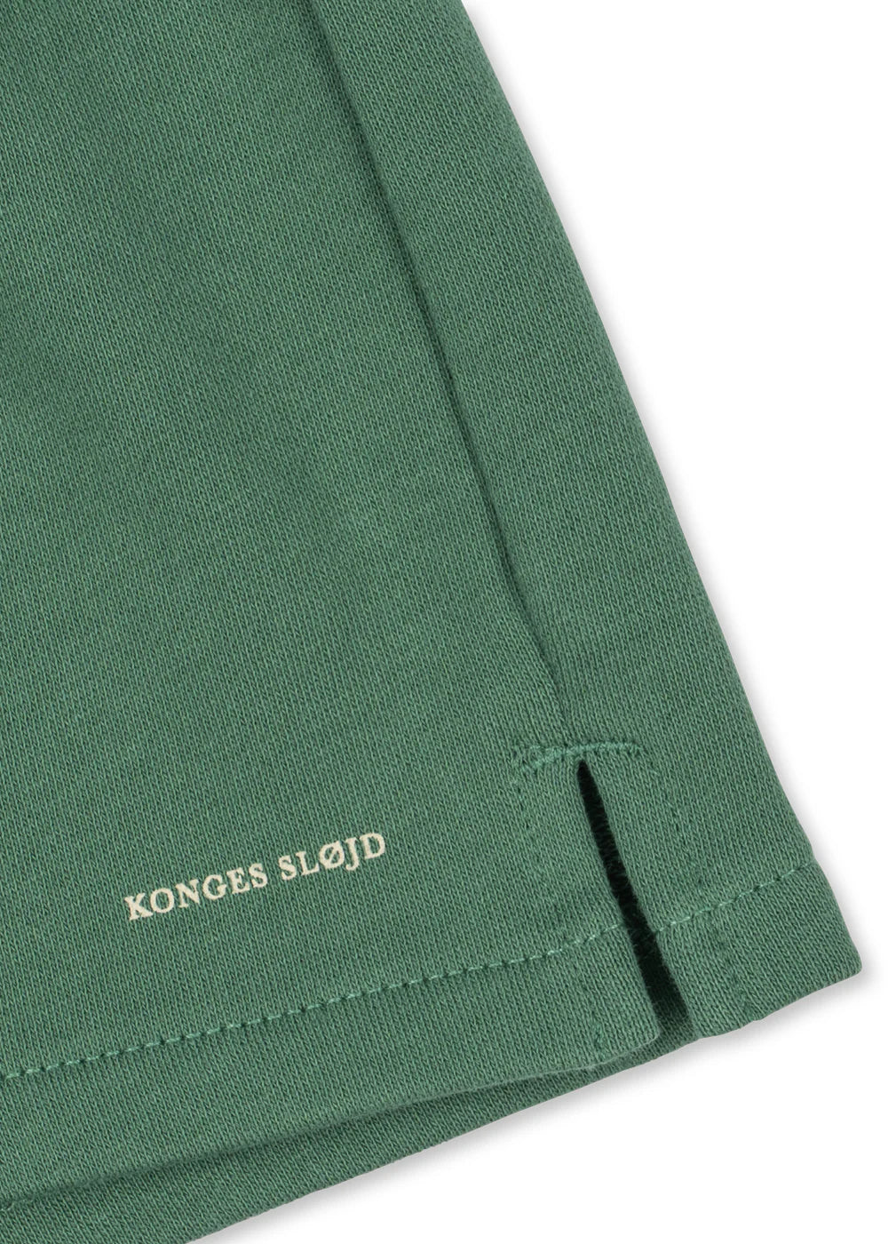 Close-up of a green fabric with 'Konges Slojd' branding on a white background