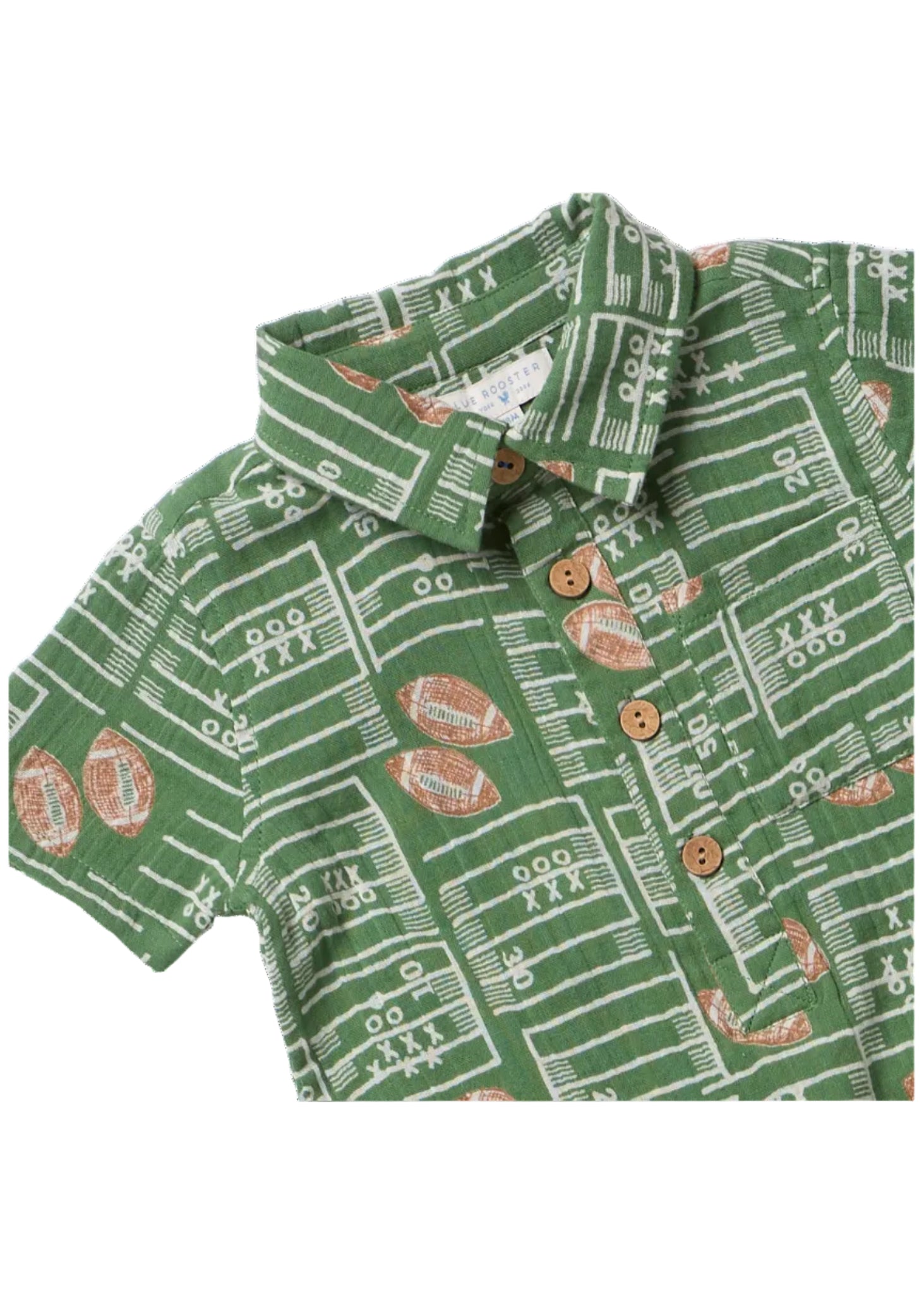 A close-up of a green short-sleeve collared shirt with a white football field line pattern and brown football motifs, featuring three brown buttons on the front.