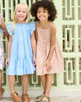 Two young girls wearing dresses standing in front of a decorative wall.