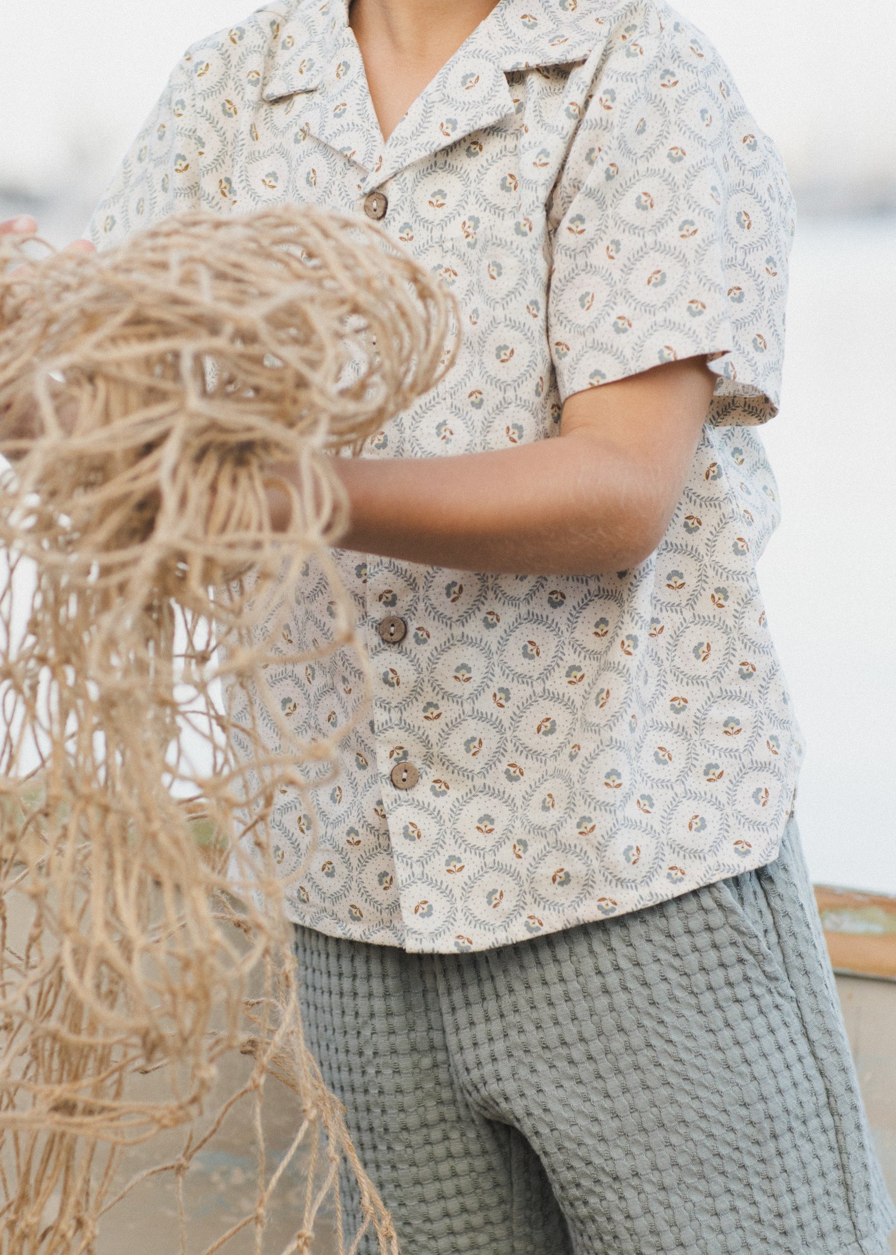 Person holding a bundle of twine or rope outdoors