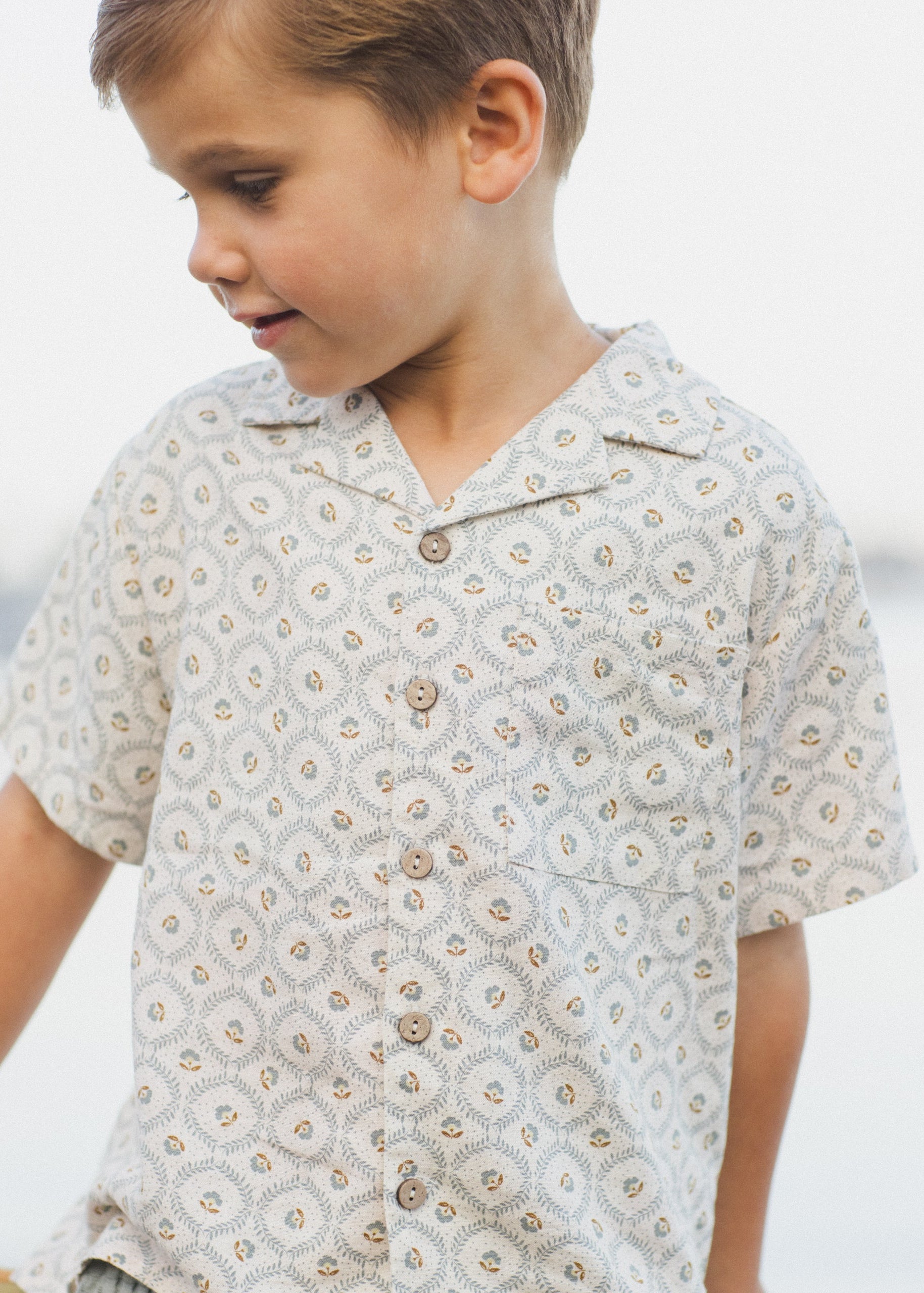 Child wearing a patterned shirt with a blurred background