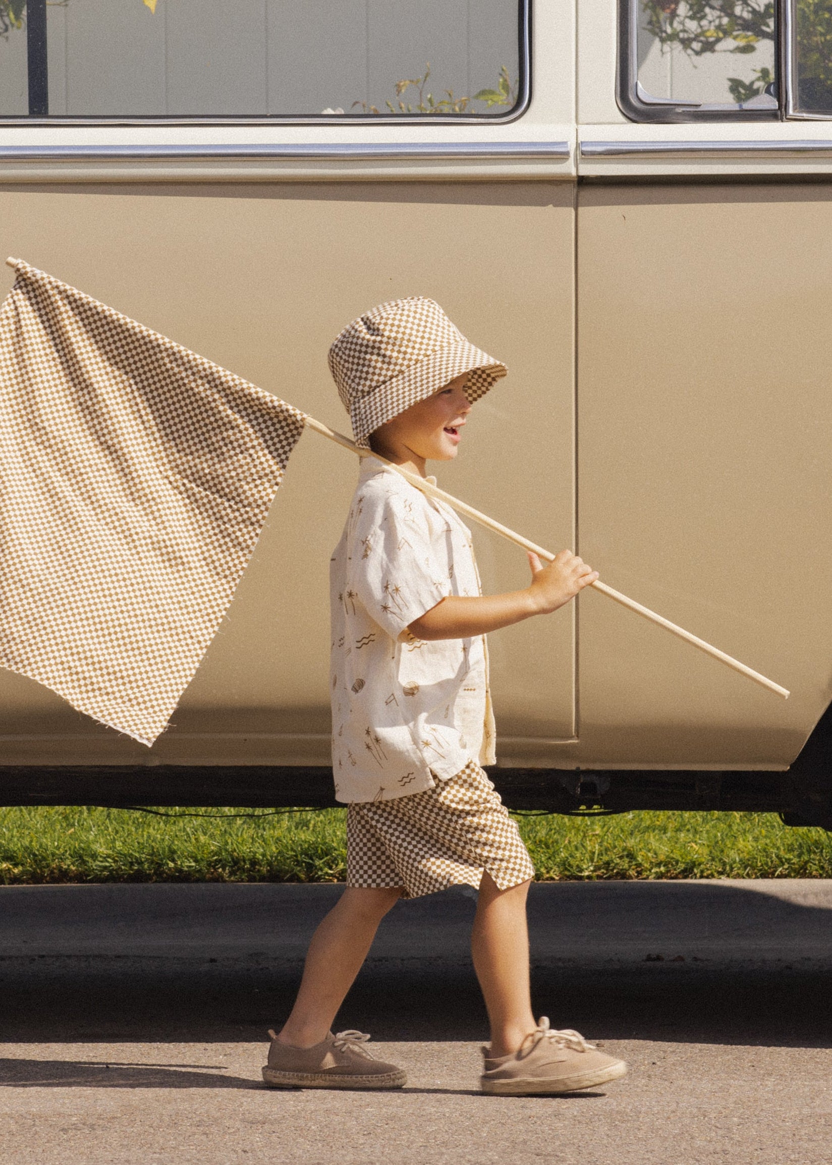 Child holding a fishing net and rod in front of a vintage van