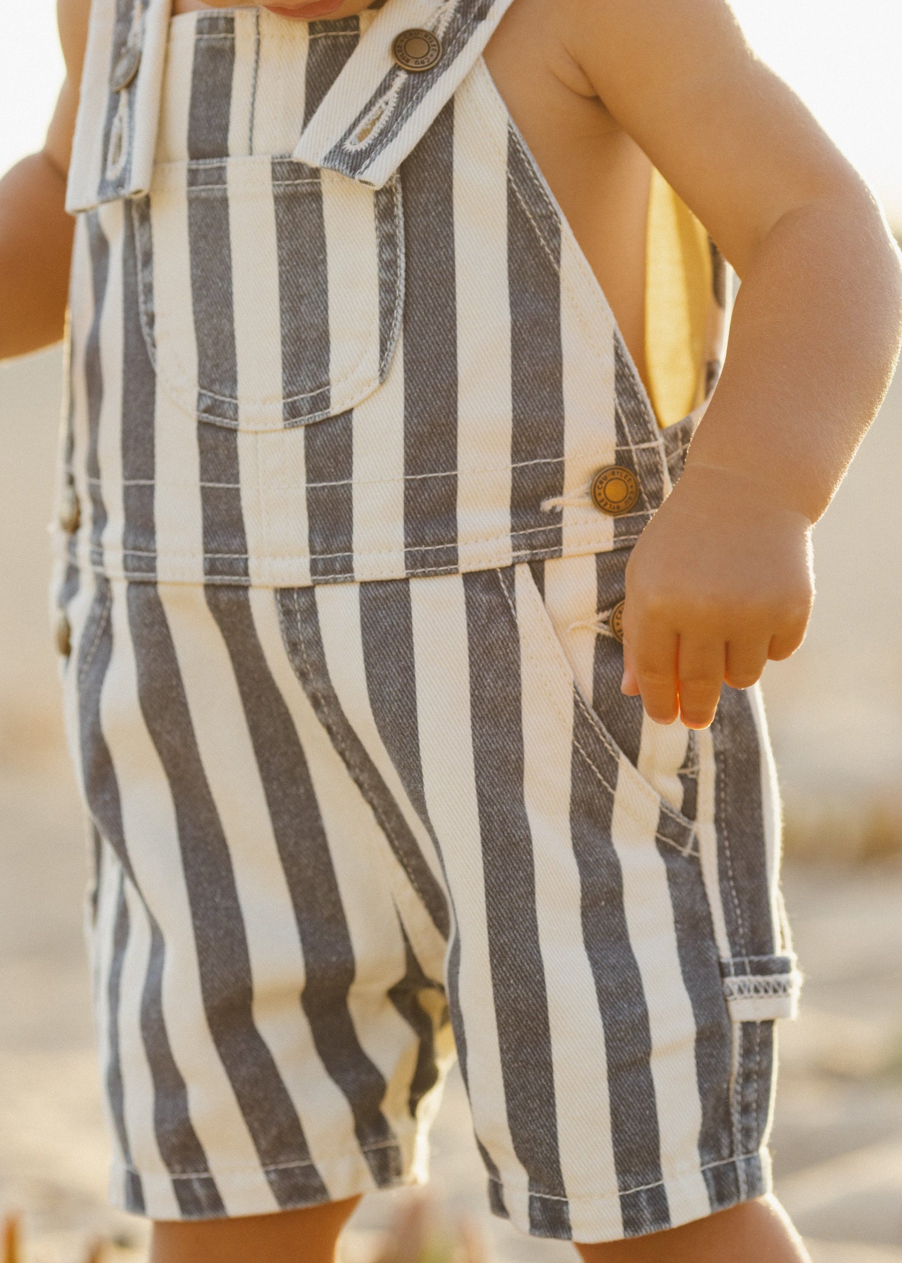 Child wearing a striped romper with a blurred natural background