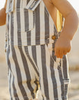 Child wearing a striped romper with a blurred natural background