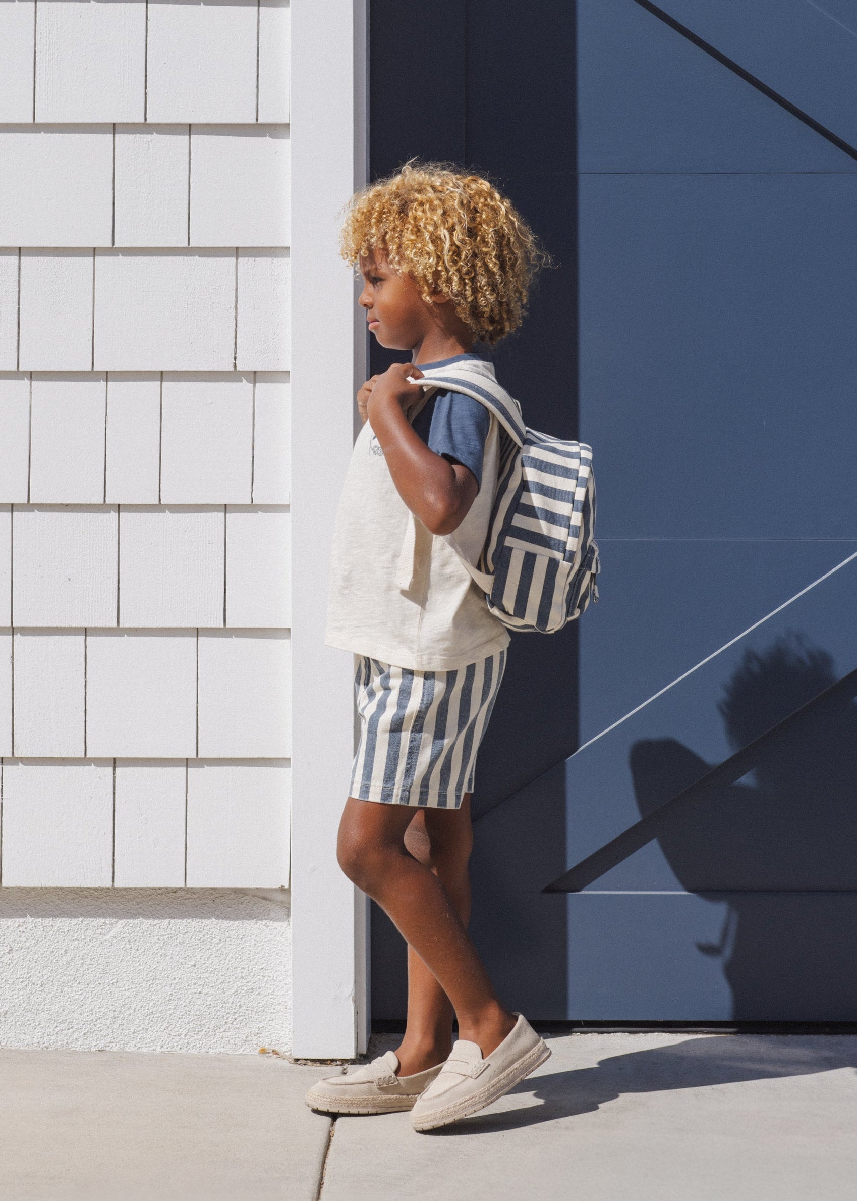 Person with a striped backpack standing against a building corner