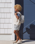 Person with a striped backpack standing against a building corner